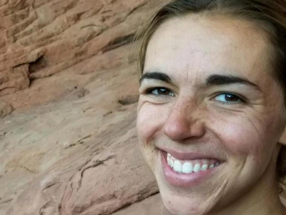 Katie Portman smiling in front of a red rock formation, wearing a navy athletic shirt.